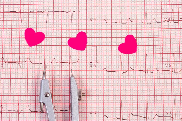 Hearts of paper and calipers on electrocardiogram graph, medicine and healthcare concept — ストック写真