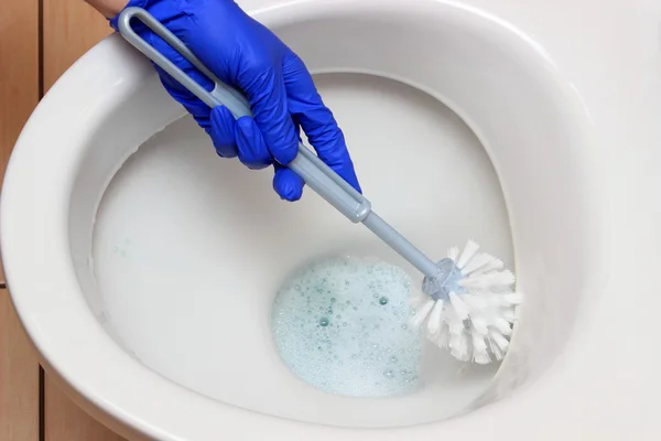 Hand einer Frau in blauem Handschuh reinigt Toilettenschüssel — Stockfoto