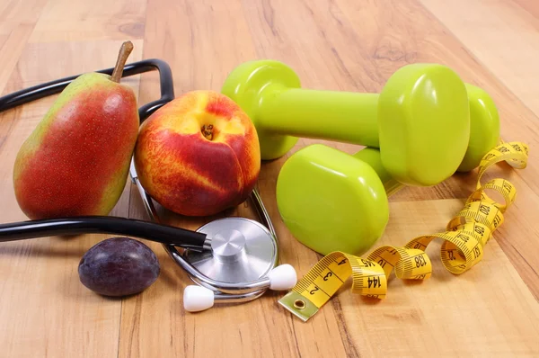 Medical stethoscope, fruits and dumbbells for using in fitness — Stock Photo, Image