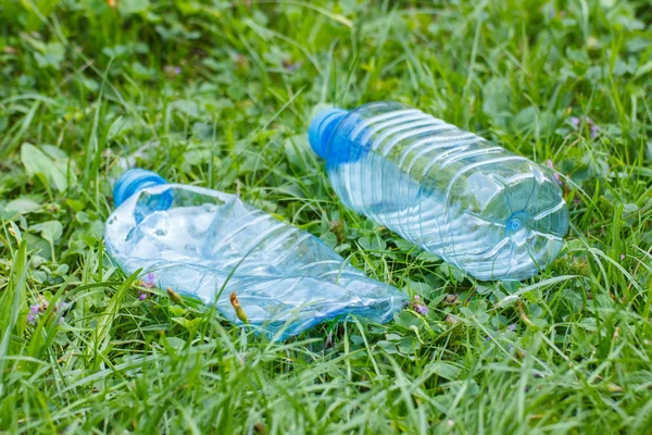 Garrafas de plástico de água mineral na grama no parque, lixo do meio ambiente — Fotografia de Stock