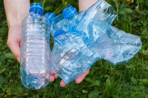 Garrafas de plástico de água mineral na mão da mulher, lixo de ambiente — Fotografia de Stock