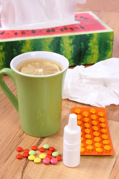 Tabletták és az orr csepp a megfázás, a zsebkendő és a forró tea citrommal — Stock Fotó