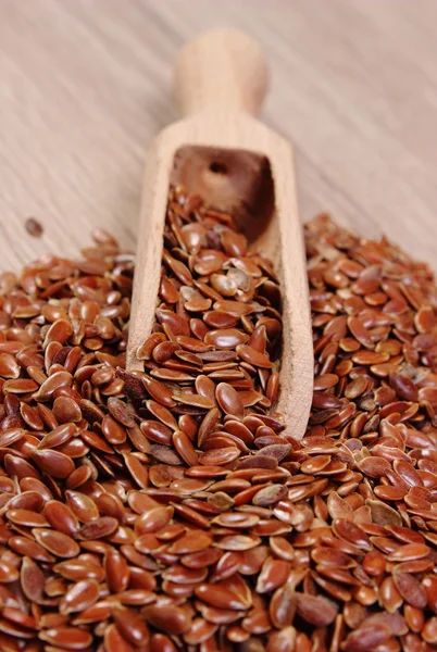 Heap of linseed with spoon on wooden background — Stock Photo, Image