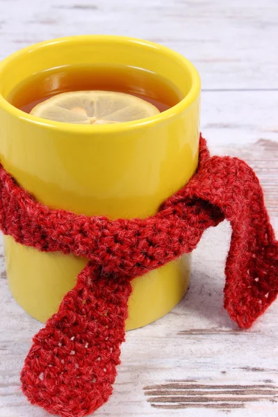 Cup of hot tea with lemon wrapped woolen scarf, warming beverage for flu and cold — Stock Photo, Image