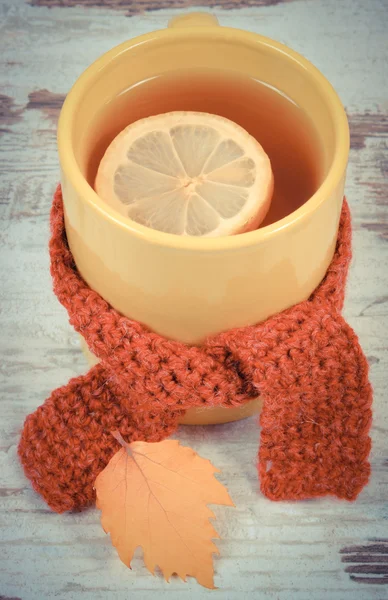 Vintage photo, Cup of tea with lemon wrapped woolen scarf and autumnal leaf — Stock Photo, Image