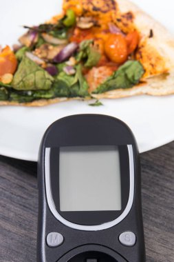 Glikoz ölçer şeker seviyesini taze pişmiş vejetaryen pizzayla ölçmek ve kontrol etmek için kullanılır. Diyabet konsepti sırasında besin