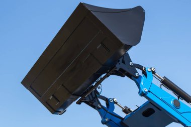 Mavi gökyüzü arka planında kazıcı küreği ya da buldozer. Hidrolik ve pnömatik mekanizma. Endüstriyel veya tarımsal makinenin parçası