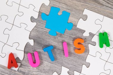 Otizm Spektrum Bozukluğunun sembolü olarak beyaz ve mavi bulmacaları, otizm yazıtlarını bir araya getiren çocuk eli. Otizm Farkındalık Günü konsepti