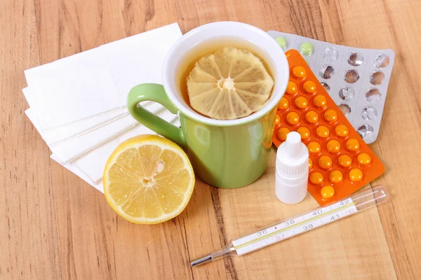 Comprimidos e gotas de nariz para resfriados, lenços e chá quente com limão — Fotografia de Stock