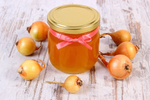 Свіжий органічний мед у скляній банці та цибулі на дерев'яному фоні, здорове харчування та зміцнення імунітету — стокове фото