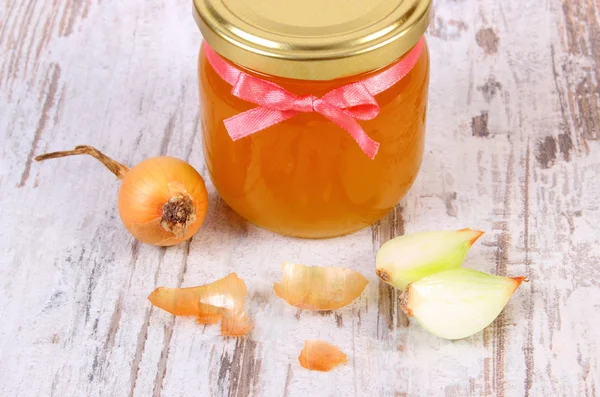 Miel orgánica fresca en frasco de vidrio y cebollas sobre fondo de madera, nutrición saludable y fortalecimiento de la inmunidad — Foto de Stock