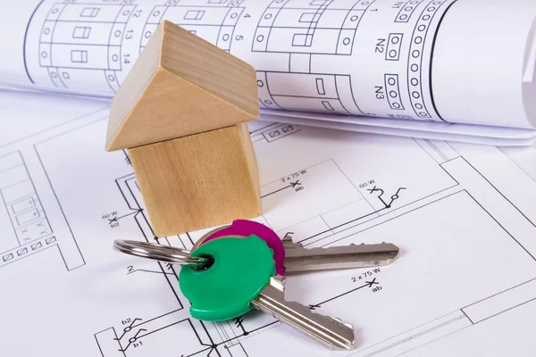 House of wooden blocks, rolls of diagrams and keys on construction drawing of house — Stock Photo, Image