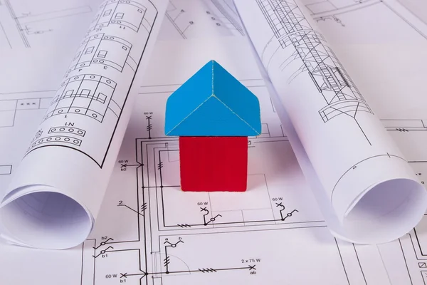 La casa de los bloques de madera y los rollos de los diagramas sobre la construcción el dibujo de la casa — Foto de Stock