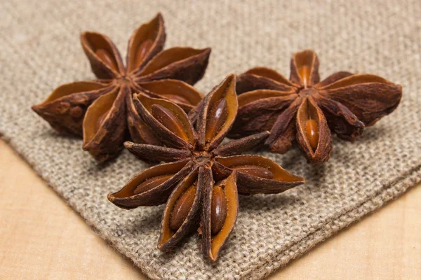 Star anise on jute canvas on wooden table, seasoning for cooking — Stok fotoğraf