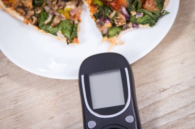 Glikoz ölçer şeker seviyesini taze pişmiş vejetaryen pizzayla ölçmek ve kontrol etmek için kullanılır. Diyabet konsepti sırasında besin