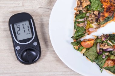 Glikoz ölçer şeker seviyesini kontrol etmek ve bir parça taze vejetaryen pizza için kullanılır. Diyabet konsepti sırasında beslenme ve fast food yeme