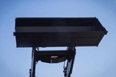 Mavi gökyüzü arka planında kazıcı küreği ya da buldozer. Hidrolik ve pnömatik mekanizma. Endüstriyel veya tarımsal makinenin parçası