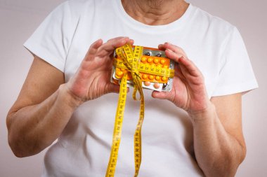 Elinde vitamin paketleri, takviyeler ve santimetre ile yaşlı bir kadın. Tedavi, zayıflama veya yaşlılıkta bağışıklığı güçlendirme. Sağlık hizmetleri