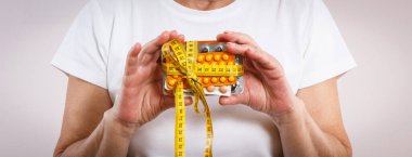 Elinde vitamin paketleri, takviyeler ve santimetre ile yaşlı bir kadın. Tedavi, zayıflama veya yaşlılıkta bağışıklığı güçlendirme. Sağlık hizmetleri