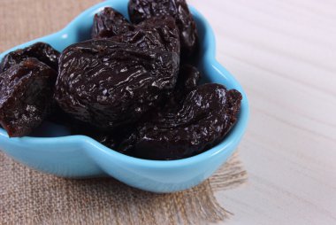 Ahşap masa, sağlıklı gıda üzerinde mavi kase kuru erik