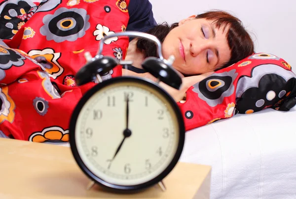 Brunette woman sleeping in her bedroom with alarm clock — Stock Photo, Image