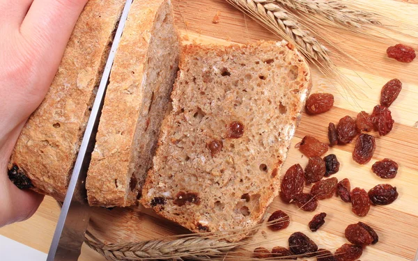 Snijden vers brood, oren van tarwe en rozijnen — Stockfoto