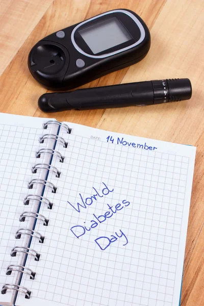 Glucometer com dispositivo de lanceta e dia mundial de diabetes escrito em notebook — Fotografia de Stock
