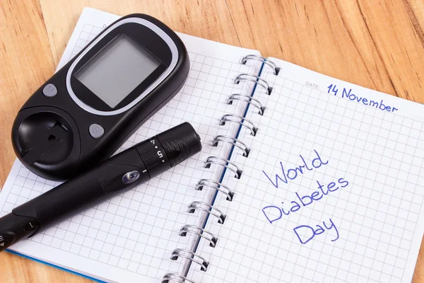 Glucometer com dispositivo de lanceta e dia mundial de diabetes escrito em notebook — Fotografia de Stock