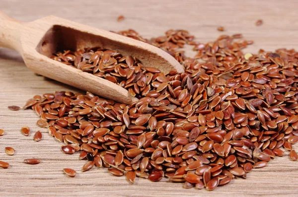 Heap of linseed with spoon on wooden background — Stock Photo, Image