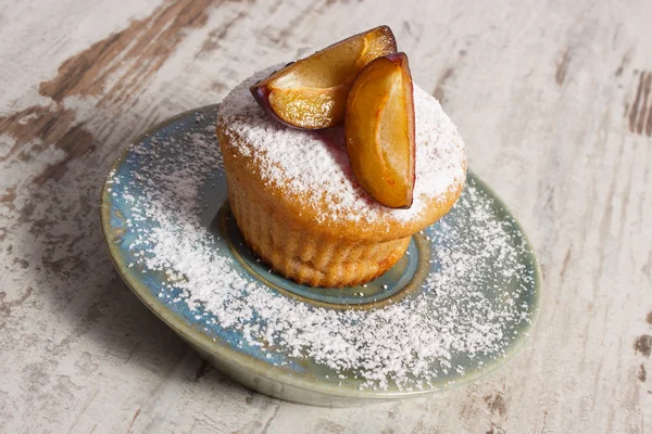 Muffin appena sfornati con prugne e zucchero a velo sul piatto, delizioso dessert — Foto Stock