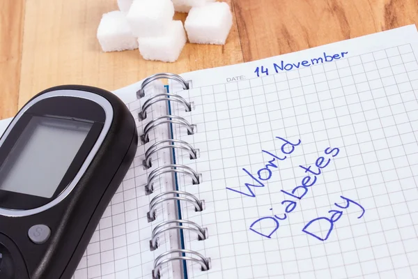 Glucometer, dia mundial da diabetes escrito em caderno e cubos de açúcar — Fotografia de Stock
