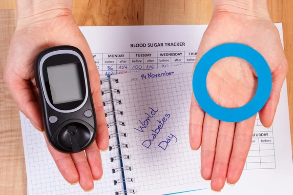 Glucometer y círculo azul en la mano, símbolo de diabético, día mundial de la diabetes —  Fotos de Stock