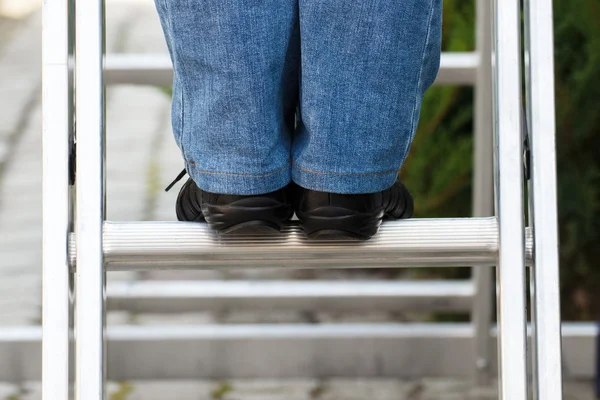 Piedi di donna su scala in alluminio in giardino — Foto Stock