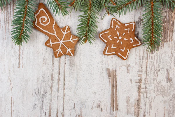 Nybakat dekorerade pepparkakor och spruce grenar på gamla trä bakgrund, juletid — Stockfoto