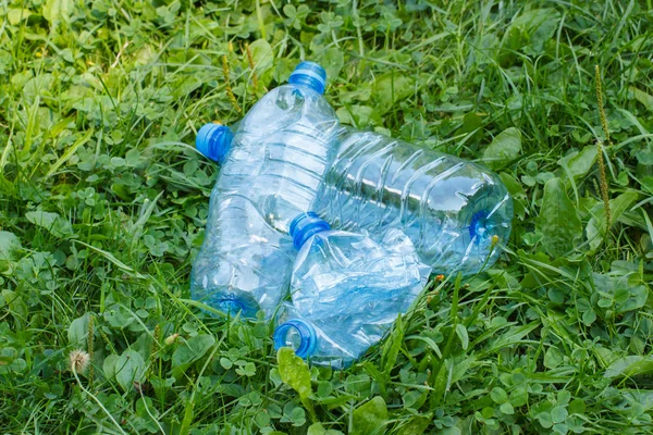 Πλαστικά μπουκάλια μεταλλικό νερό στο γρασίδι στο πάρκο, συσσώρευση απορριμμάτων του περιβάλλοντος — Φωτογραφία Αρχείου