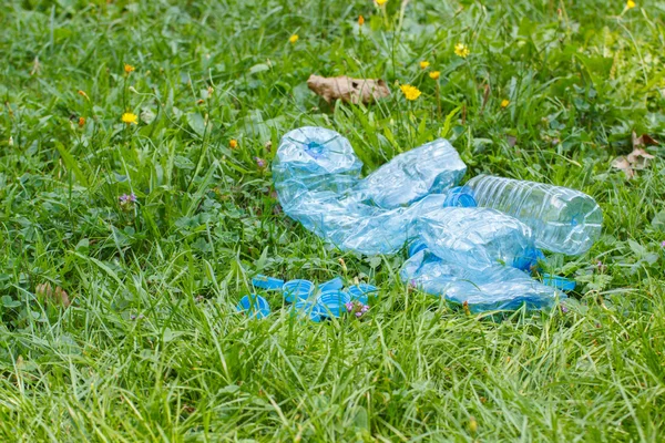 Garrafas de plástico e tampas de garrafa na grama no parque, lixo do meio ambiente — Fotografia de Stock