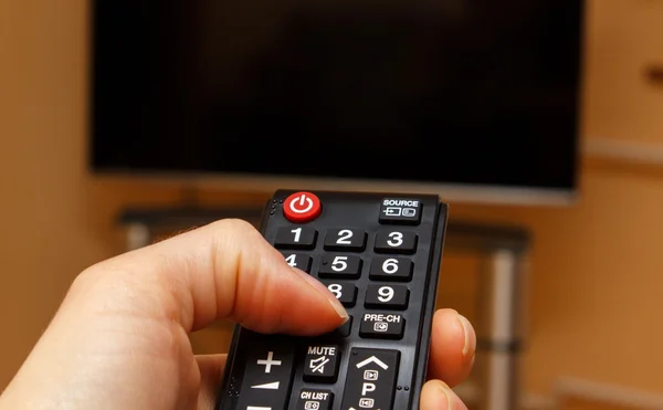 Hand holding remote control for television, choosing channel in TV — Stock Photo, Image