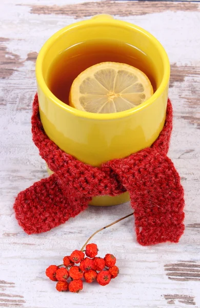 Cup of hot tea with lemon wrapped woolen scarf, warming beverage for flu, autumn decoration — Stock Photo, Image