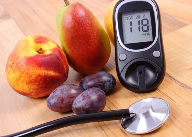 Glucose meter with medical stethoscope and fresh fruits, healthy lifestyle