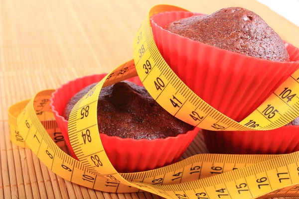 Chocolate muffins in red cups and tape measure — Stock Photo, Image