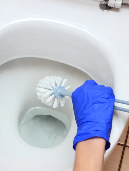Main de femme en gant bleu nettoyage cuvette de toilette — Photo