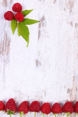 Fresh raspberries with leaf and copy space for text on old wooden background