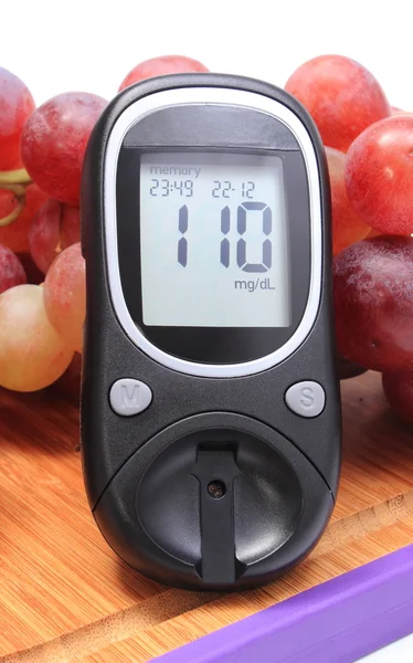 Glucose meter and fresh natural grapes on cutting board — Stock Photo, Image