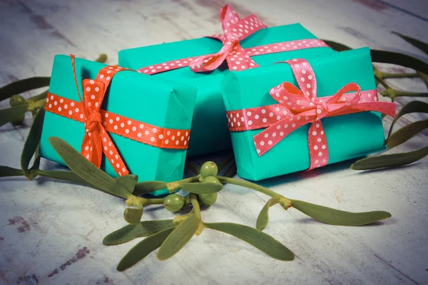 Vintage photo, Wrapped green gifts for Christmas and mistletoe on old wooden background — Stock Photo, Image