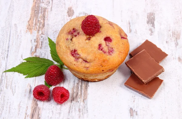 Fresh baked muffins with raspberries and chocolate on wooden background, delicious dessert — Stock Photo, Image