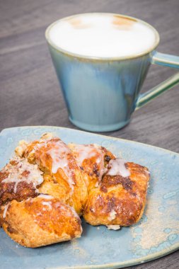 Açık mavi tabakta haşhaş tohumu ve bir fincan kahveyle birlikte taze pişmiş ciladan yapılmış hamur işi. Geleneksel Martin kruvasanları Polonyalı Poznan 'dan.