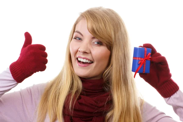 Smiling woman in woolen gloves with wrapped gift for Christmas showing thumbs up — Zdjęcie stockowe