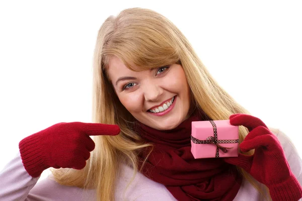 Smiling woman in woolen gloves showing wrapped gift for Christmas or other celebration — Stockfoto