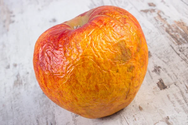 Spoiled apple on old wooden white table — Stock Photo, Image