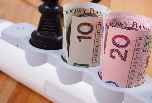 Rollos de dinero de moneda polaca en la tira de energía eléctrica con enchufe conectado, costos de energía — Foto de Stock